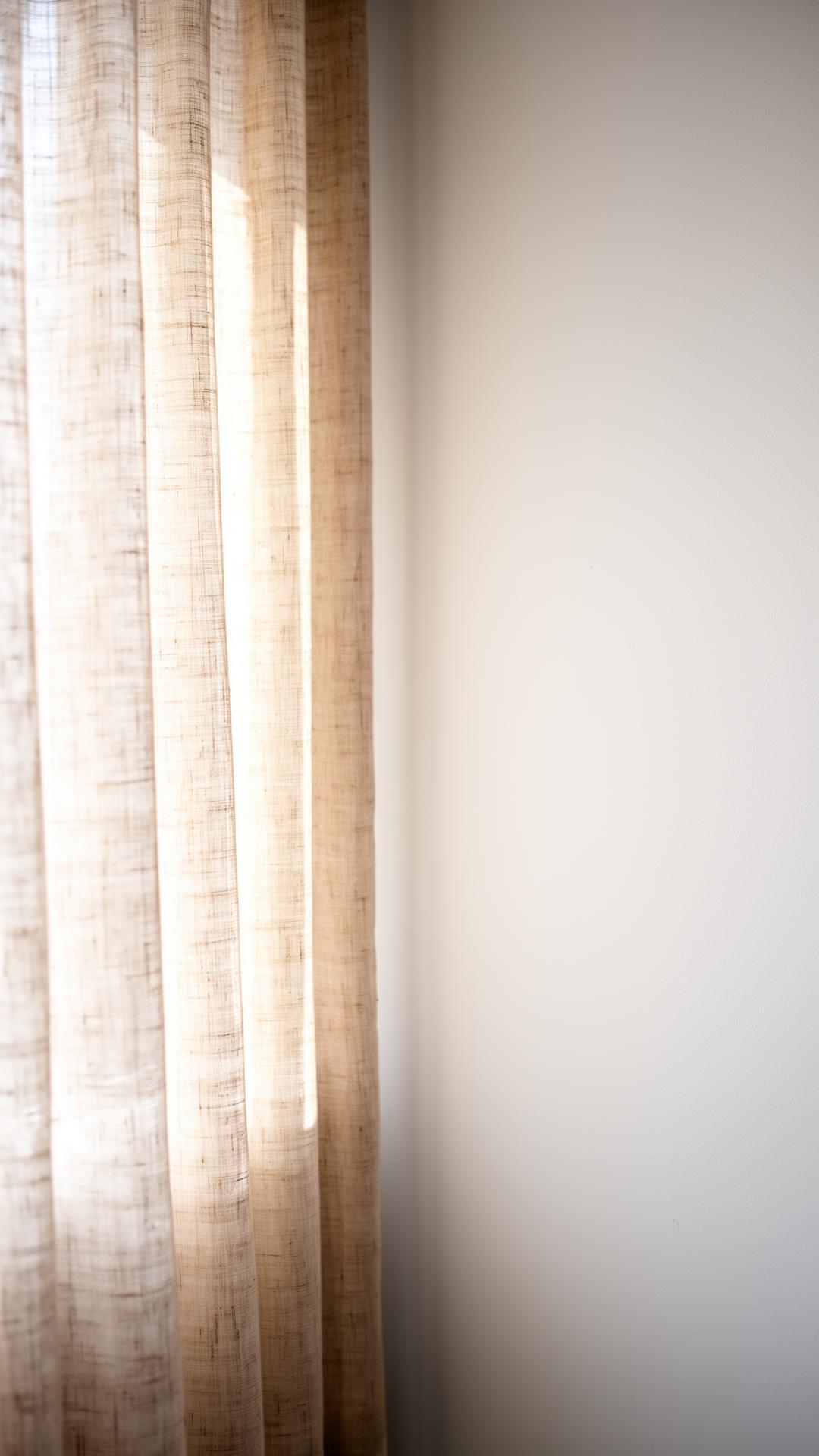 Soft daylight through a linen curtain against a plain wall
